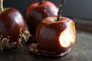 Delectable Caramel Apples On A Rustic Table Wallpaper