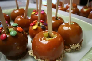 Delicious Caramel Apples On A Wooden Table Wallpaper