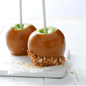 Delicious Caramel Apples On Wooden Table Wallpaper
