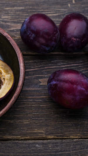 Delicious Italian Prune Blood Plums Against A Dark Background Wallpaper