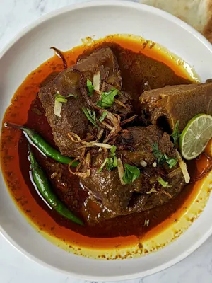 Delicious Nihari Served With Garnishing On A Wooden Table Wallpaper