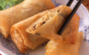 Delicious Sliced Egg Rolls Served With Chopsticks Wallpaper