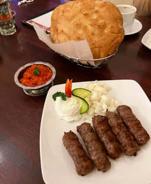 Delightful Dish Of Ćevapi Sausages And Fresh Pita Bread Wallpaper