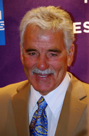 Dennis Farina Posing For A Photo With His Iconic Smile Wallpaper