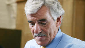 Dennis Farina Smiling On A Blue Background Wallpaper