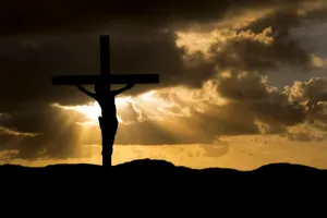 Depiction Of Christ's Crucifixion On A Cross Against A Dramatic Sky Wallpaper