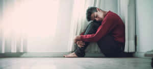 Despondent Individual Seatedon Floor Wallpaper