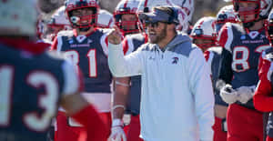 Determined Football Coach Strategizing A Game Plan Wallpaper