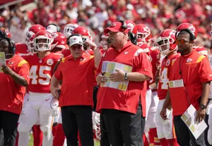 Determined Football Coach Studying Game Strategy Wallpaper