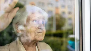 Dignified Aging: A Serene Elderly Woman Peering Through The Glass Wallpaper