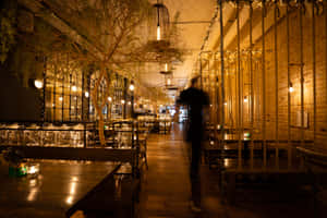 Dimly Lit Restaurant Interiorwith Person Walking Wallpaper