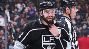 Drew Doughty Smiling With Missing Teeth While Holding Helmet Strap Wallpaper