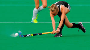 Dynamic Female Field Hockey Player In Action Wallpaper