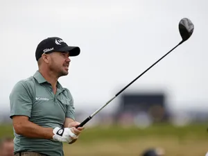 Dynamic Moment Of Brian Harman, Raising His Golf Club During A Match Wallpaper