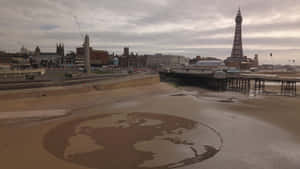 Earth Sculpture In The Sands Near The Iconic Blackpool Tower Wallpaper