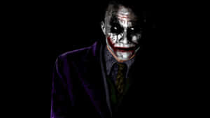 Eerie Evil Joker Grinning Menacingly In A Dark And Sinister Atmosphere Wallpaper