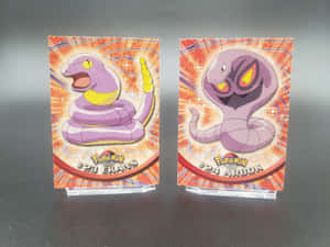 Ekans And Arbok Cards On Blurry Gray Background Wallpaper