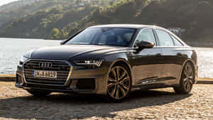 Elegant Audi A6 On A Scenic Road Wallpaper