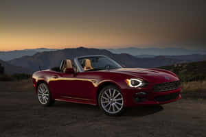 Elegant Fiat 124 Spider Cruising On The Road Wallpaper