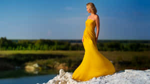 Elegant Woman In A Stylish Yellow Dress Wallpaper