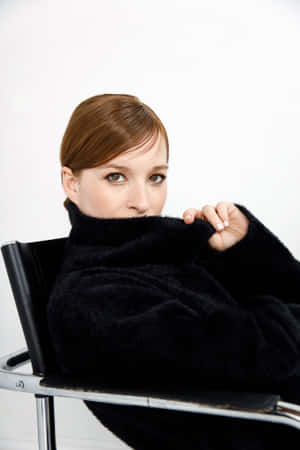 Elegant Woman Peering Over Black Sweater Wallpaper