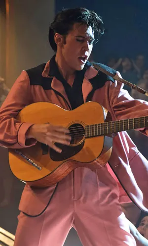 Elvis Presley In Pink Suit Playing Guitar Wallpaper