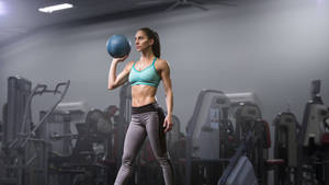 Empowered Female Lifter Focusing On Her Fitness Goals Wallpaper