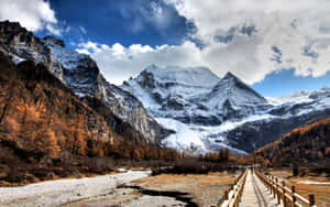 Enjoy A Serene Landscape Of Snow-capped Mountains Wallpaper