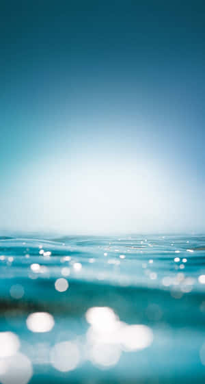 Enjoy A Surreal View Of The Blue Ocean Through The Water Iphone Wallpaper