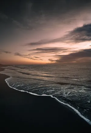 Enjoy An Afternoon At A Beautiful Black Sand Beach Wallpaper