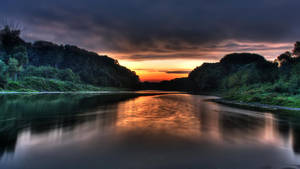 Enjoy Peaceful Serenity Along A Jungle River At Sunset Wallpaper
