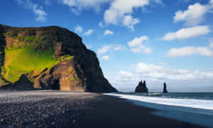 Enjoy The Crystal Clear Views Of The Picturesque Black Sand Beach. Wallpaper