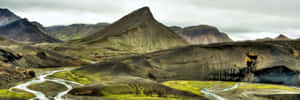 Enjoy The Freshness Of Nature With This Majestic View Of A Green Field Surrounded By Hills On A Spring Day Wallpaper