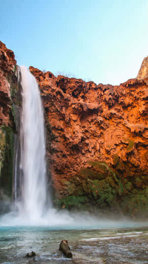 Enjoy The Peaceful Beauty Of Nature With A Breathtaking View Of A Waterfall Wallpaper