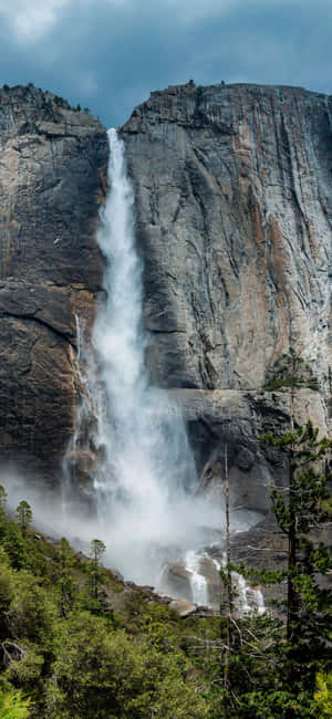 Enjoy The Serene And Soothing Backdrop Of A Beautiful Waterfall Wallpaper