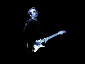 Eric Clapton Illuminated By Blue Stage Lights Wallpaper