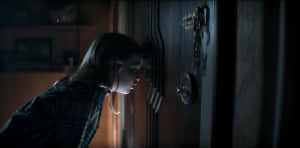 Evil Dead Rise Suspenseful Door Peeking Wallpaper