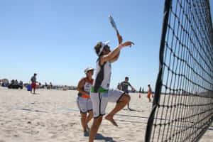 Exciting Beach Tennis Match In Action Wallpaper