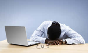 Exhausted Office Worker Restingat Desk Wallpaper