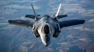 F35 Jet In Flight Over Landscape.jpg Wallpaper