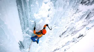 Fearless Ice Climber Ascending A Frozen Waterfall Wallpaper