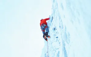 Fearless Ice Climber Conquers A Frozen Waterfall Wallpaper