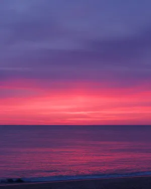 Feel The Warmth Of The Setting Sun On A Beautiful Pink Beach Wallpaper