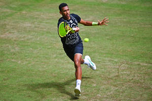 Felix Auger Aliassime In Action On A Grass Court Wallpaper