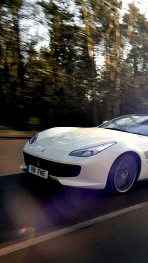 Ferrari F12tdb - A White Sports Car Driving Down A Road Wallpaper