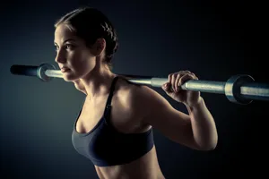 Focused Female Athlete Barbell Workout Wallpaper