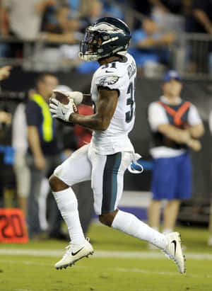 Football Player Catching Ball Action Shot Wallpaper