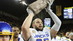 Football Player Celebratingwith Paper Bag Trophy Wallpaper