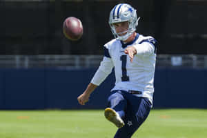 Football Player Punting Ball During Practice Wallpaper