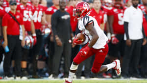 Football Player Running With Ball During Game Wallpaper